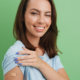 Geimpfte Frau zeigt Plaster auf Oberarm